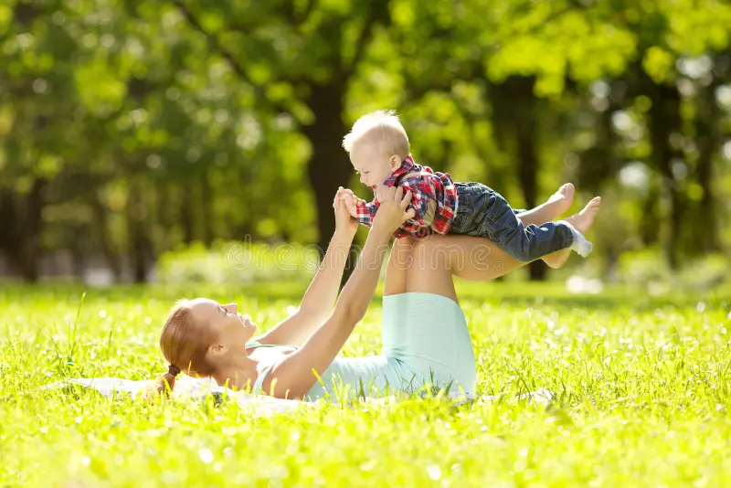 Mother and baby playing on the grass in a sunny park